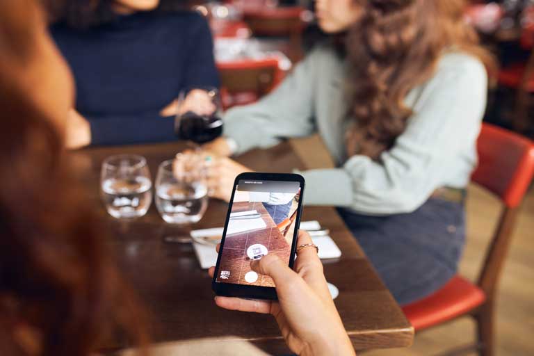 Mujer escaneando un menu digital en la mesa de un restarante