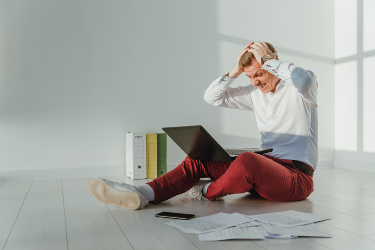 Profesional preocupado agarrándose la cabeza en frente de un computador