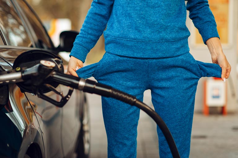 Persona revisando los bolsillos vacíos de su pantalón en una estación de gasolina