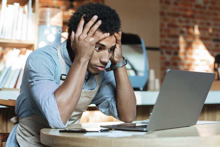 Frustrated young business owner looking at a computer