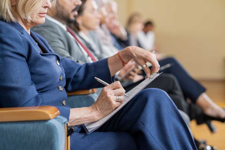 Trabajadores de el gobierno sentados en una conferencia tomando notas