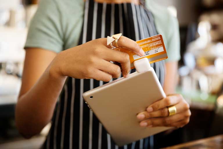 Mujer deslizando una tarjeta de credito en un dispositivo de pago agregado a un ipad
