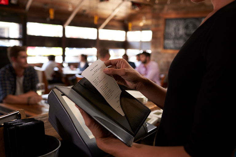 Mesera alistando el recibo de la cuenta para una mesa en un restaurante